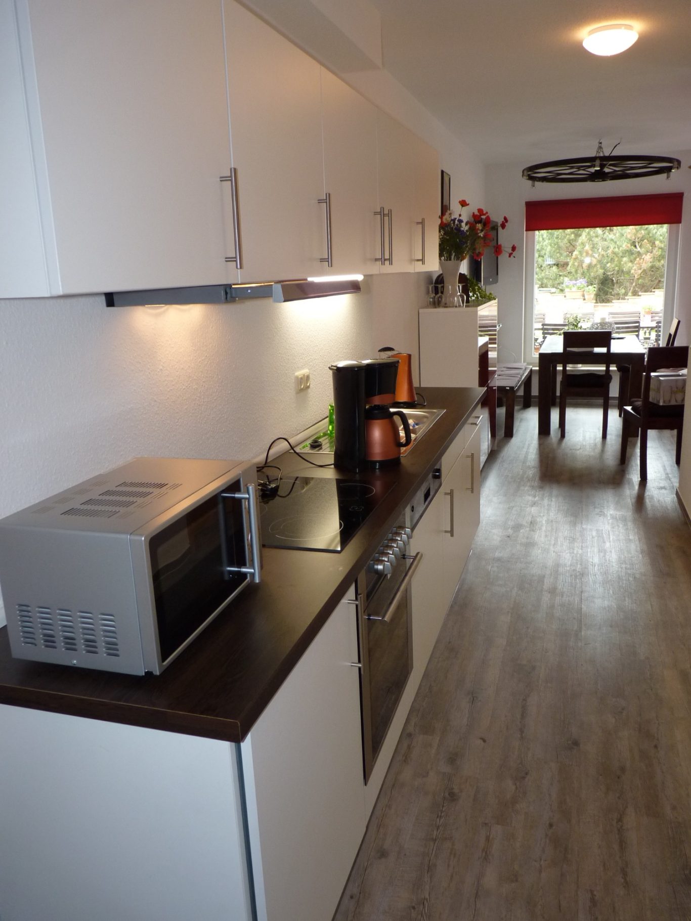 Küche Moderne Küche mit Mikrowelle, Herd, Spüle und Essbereich im Hintergrund.