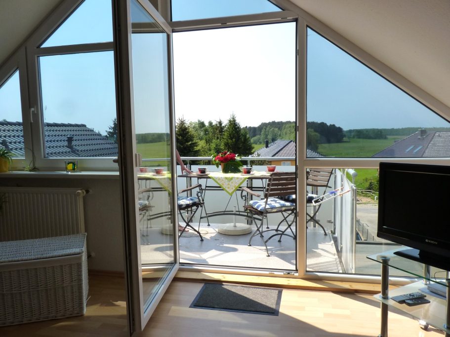 Balkon Atelier Heller Wohnraum mit Balkon, Stühlen, Tisch und Blick ins Grüne.