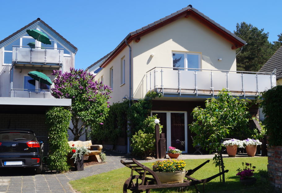 Wohnhaus Helles Wohnhaus mit Balkon, Gartenmöbeln und blühenden Pflanzen im Hof.